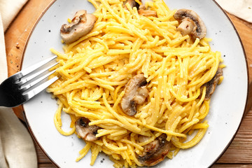 Plate with tasty pasta and mushrooms on table