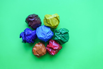 Crumpled paper balls up piece of paper on green background.
