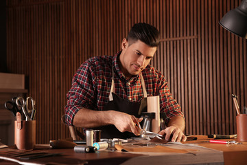 Man cutting leather with scissors in workshop