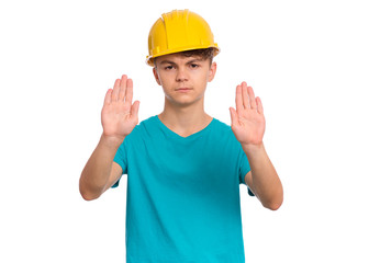 Handsome Teen Boy wearing yellow Hard Hat doing stop sign with palm of hands. Portrait of serious Child making stop gesture and Looking at camera, isolated on white background.