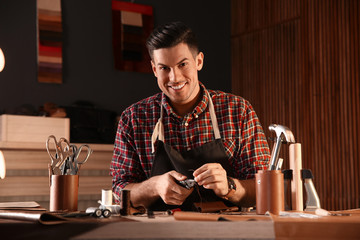 Man sewing piece of leather in workshop