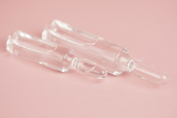Glass medical ampoules on a pink background close-up, copy space,selective focus,macro photo.
