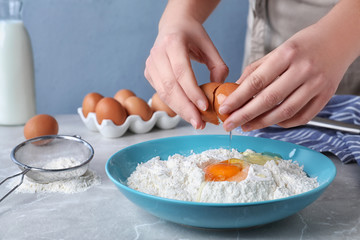 Woman preparing batter for thin pancakes at light grey table, closeup