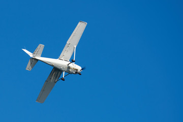 White small plane, rusted on bottom, making a turn in the sky
