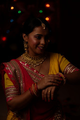 Portrait of an Indian Bengali beautiful brunette woman in front of the colorful light bokeh background created by tiny chain lights  in the evening of Diwali. Indian lifestyle and religion.