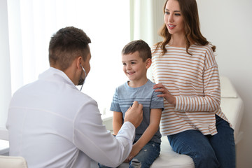 Mother and son visiting pediatrician. Doctor examining little patient with stethoscope in hospital