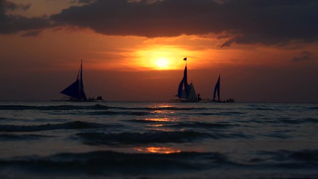 Silhouette Paraw sailing boats under orange sunset at Boracay Island of Philippines 60fps