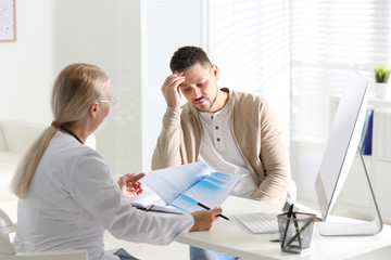 Doctor consulting patient at desk in clinic