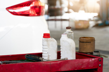 Fototapeta na wymiar Engine oil bottle, hand tool rack Where the background blur is the back of a car in the garage.