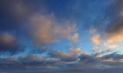 Fototapeta na wymiar Dark clouds lit by the evening sun with gleams of blue sky.