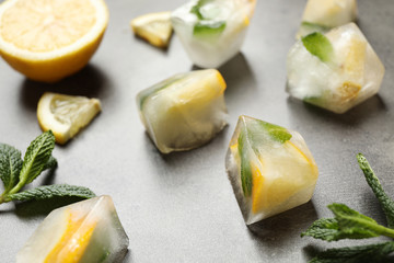 Ice cubes with lemon and mint on grey table, closeup