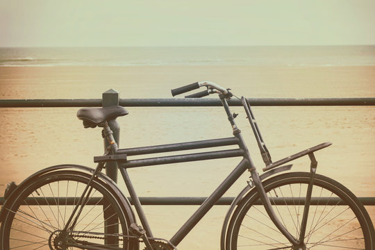 Vintage styled image of the Dutch beach with a black retro bicycle in Scheveningen