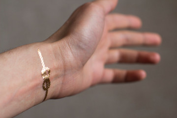 hand of a young woman wih gold sailors knot temporary tattoo on her wrist
