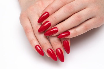Classic red nails. Red manicure on long sharp nails closeup on a white background. Shape nails...