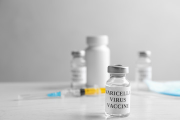 Chickenpox vaccine and syringe on white wooden table, space for text. Varicella virus prevention