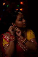 Portrait of an Indian Bengali beautiful brunette woman in front of the colorful light bokeh background created by tiny chain lights  in the evening of Diwali. Indian lifestyle and religion.