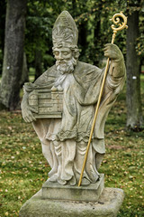 Statue of the priest holding model of church and golden crutch