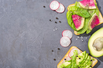 top view of organic vegetarian toasts with fresh vegetables on table with pepper seeds and salt