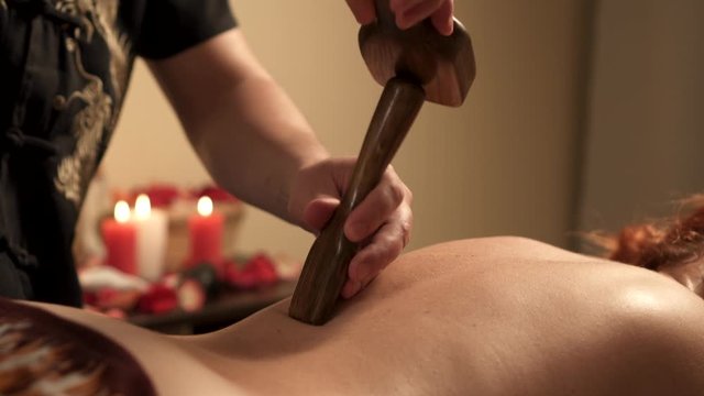 Close-up of the hands of a masseur conducting a hammer therapy massage session.