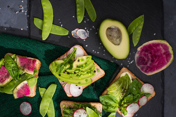 top view of vegetarian healthy sandwiches with fresh vegetables on cloth and stone board