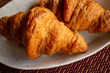 Two delicious croissants on a white plate, close up 二つの美味しそうなクロワッサンのクローズアップ