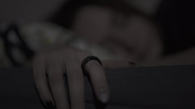White woman with brunette hair sleeping with a smart ring on her finger, tracking her sleep. Close-up.