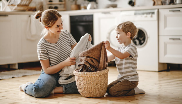 Happy Family Mother Housewife And Child   In Laundry With Washing Machine .