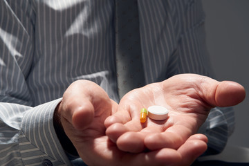 Fototapeta premium businessman with a pill, hands close view - concept of difficulties, depression, problems, health and stress, risk of modern business