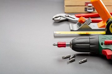 Planer, screwdriver, pincers and other household tools on a gray background. Studio photo, copy space.