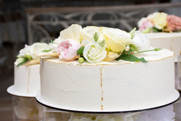 Obraz na płótnie Canvas white cake decorated with fresh flowers roses at a wedding