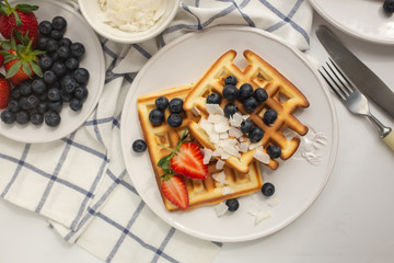 Fototapeta na wymiar Beautiful breakfast: Viennese Belgian waffles decorated with berries, a plate with strawberries and blueberries