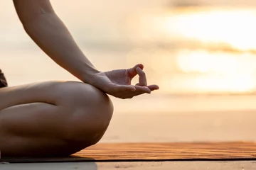 Rolgordijnen Close-up hand van vrouw praktijk yoga meditatie lotus houding op het strand in thailand, zo comfortabel voelen en ontspannen in vakantie met gouden licht, gezond concept, warme toon © 220 Selfmade studio