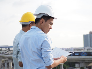 asian male engineer wear constructor helmetor foreman and architects Asian people discussing blueprint of future building or check documents and business workflow.
