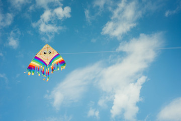 Colorful kite flying against the blue sky with clouds