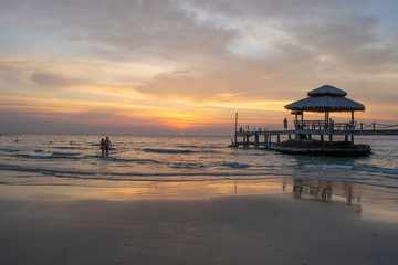 sunset on the beach , couple in love walking into the tropical sea with gold light