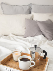 Fototapeta na wymiar breakfast in bed: a mug with black coffee, a coffee pot and a candle on a wooden tray