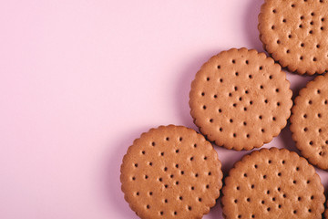 Chocolate sandwich cookie with cream, sweet food from store, on pink pastel background, top view