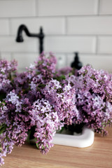 Spring flowering lilac. Bouquet of purple lilac in a white vase on a white background close-up. Selective focus. 