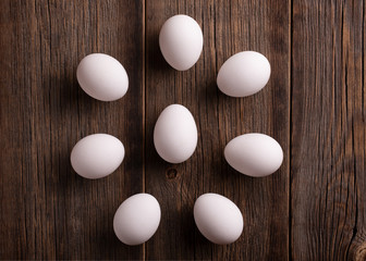 White eggs on a wooden table top view. Fresh chicken eggs on a wooden background. The concept of homemade rustic products.