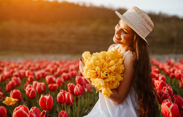 Cheerful woman with bouquet in tulip field