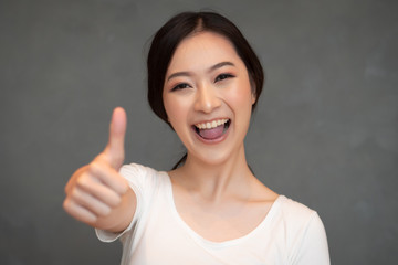 successful girl pointing thumb up; portrait of cheerful smiling woman pointing up approving, yes,...