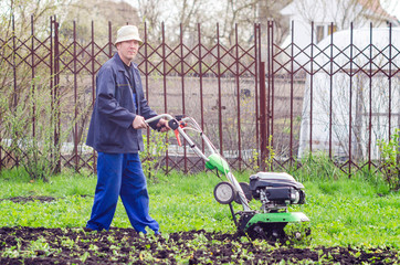 A man cultivates the land with a cultivator in a spring garden