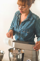 Confectioner girl in a denim shirt is preparing a cake. Concept ingredients for cooking flour products or dessert. 