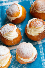 Fresh semla (vastlakukkel in Estonia) on the retro cotton tablecloth. Traditional sweet bun with whipped cream made in Scandinavic and Baltic countries for Shrove Tuesday or related days