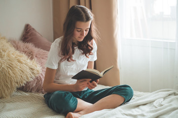 Christian teenage girl holds bible in her hands. Reading bible in a the living room. concept for...
