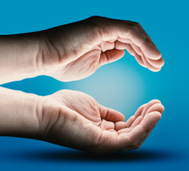 Two Human Hands with Empty Space on Blue Background. Energy - Light and Power Concept. Future Product Presentation.