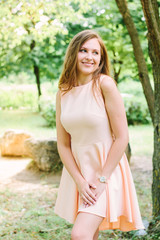 Beautiful young woman standing at park and smiling