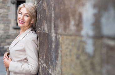 Elegant mature woman is posing near old wall