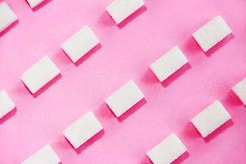square small white cubes of refined sugar on a pink background