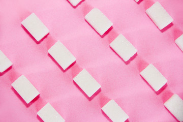 square small white cubes of refined sugar on a pink background